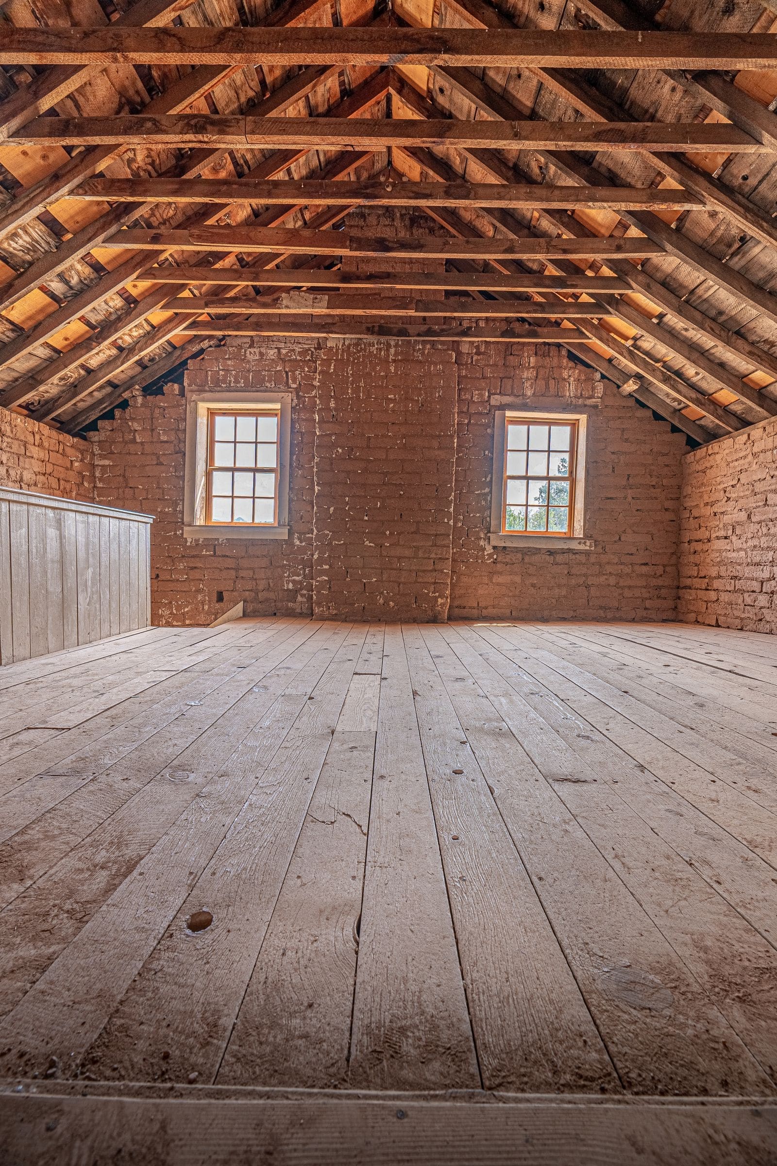 Empty attic with exposed roof framing and wood floor